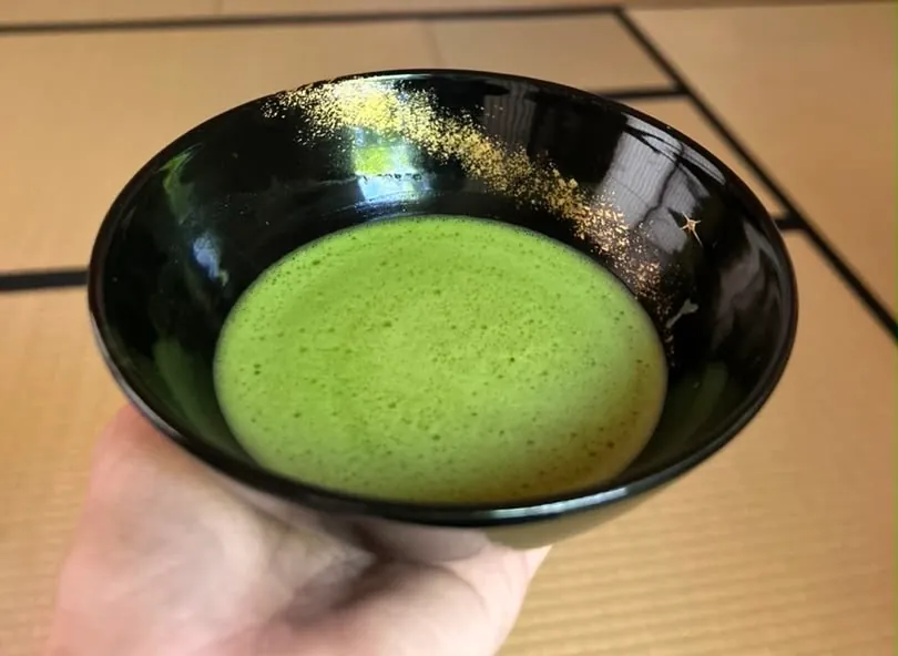 A bowl of koicha held in the hand over tatami