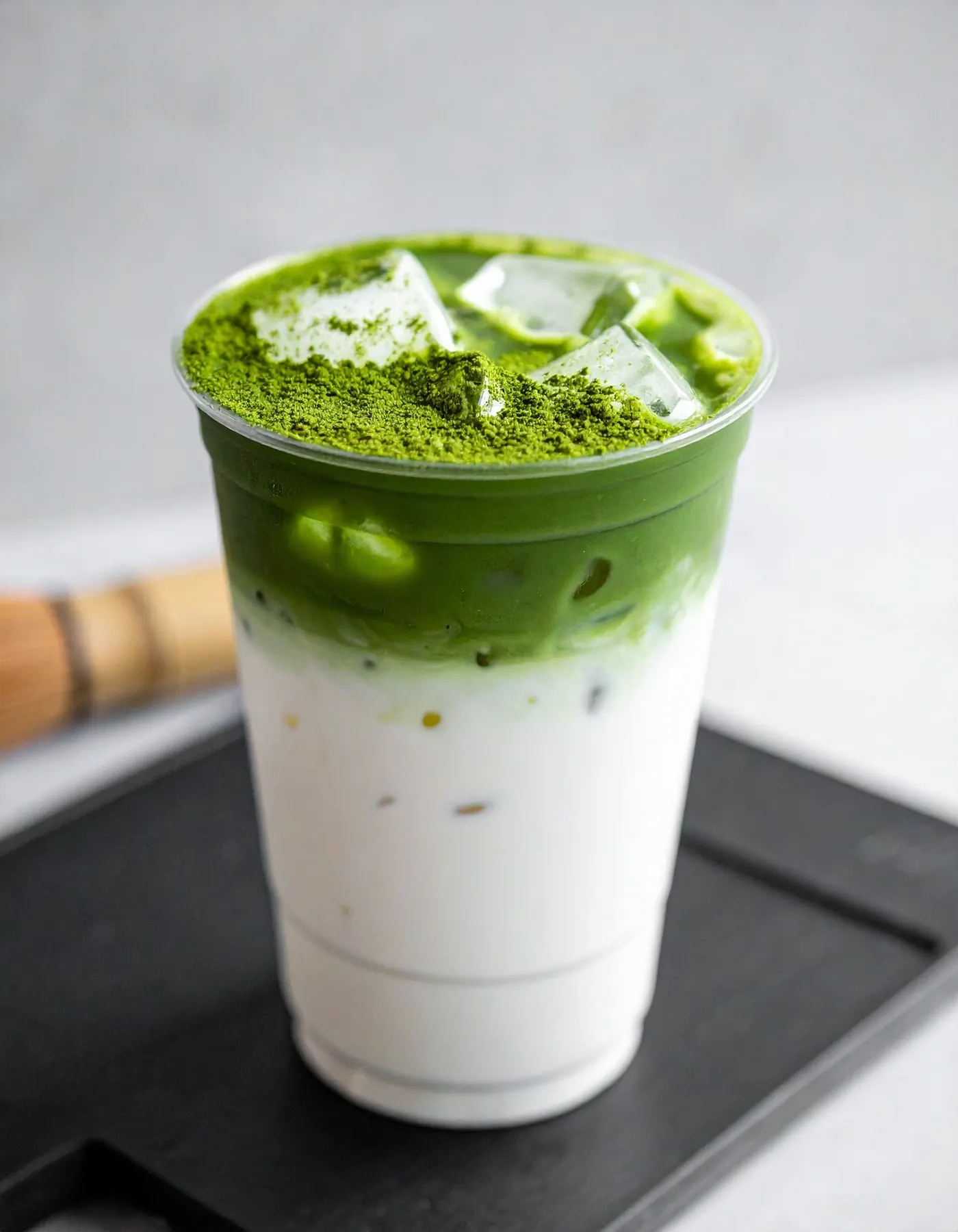 Iced matcha latte layered over milk, with matcha dusted on ice
